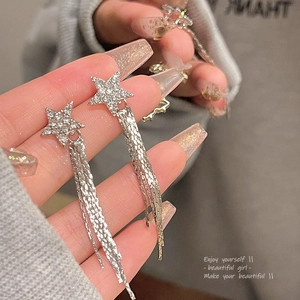 Close-up of star shaped tassel earrings with sparkling rhinestones and long metal chains