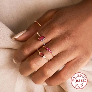 Close-up of 925 sterling silver rings with red zircon stones on beige fabric
