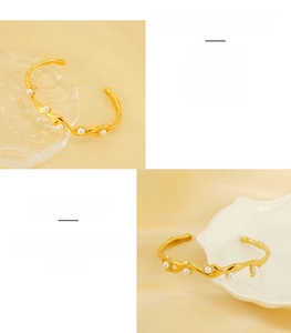 Dettaglio macro del bracciale in acciaio dorato con perle e trama ondulata