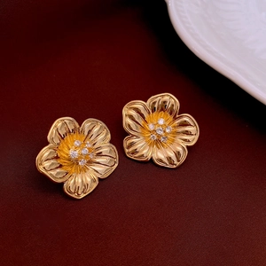 Detailed view of 18k gold plated flower stud earrings with zircon inlay on dark fabric
