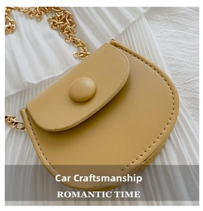Détail d'un mini sac selle en cuir jaune gingembre avec chaîne dorée et boucle ronde
