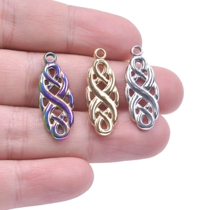 Detailed view of stainless steel witch knot charms in gold, silver, and iridescent finishes