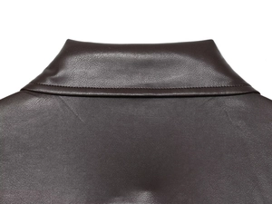 Détail du col à revers et des surpiqûres de qualité sur un manteau en similicuir marron foncé