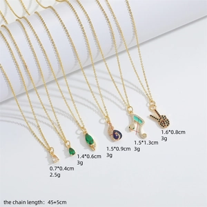 Gold pendant necklace with zircon snake and musical note charms on a white background