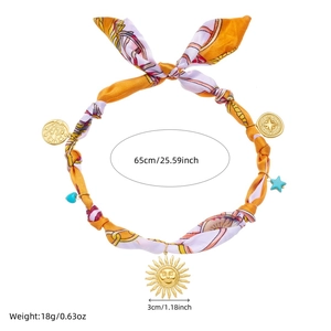 Detail view of printed silk scarf necklace with golden sun pendant and size annotations