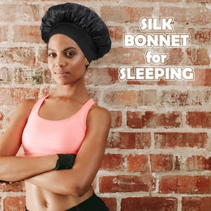 Detail of a black silk bonnet for sleeping with white English text on a brick background