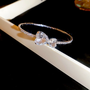 Detailed macro view of silver open bracelet featuring double heart-shaped cubic zirconia stones