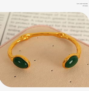 Detail of 18k gold plated open cuff bracelet with dual green cat-eye stones