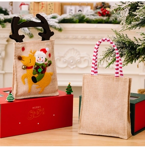 Detail of Christmas burlap gift bags featuring reindeer embroidery and striped ribbon handles