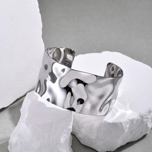 Detailed macro shot of a wide silver stainless steel cuff bracelet with hammered texture
