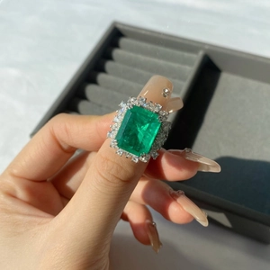 Macro detail of emerald-cut green gemstone ring with white zircon halo on S925 silver