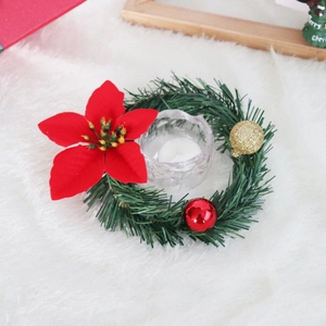 Macro view of poinsettia Christmas candle wreath with gold glitter balls and glass cup