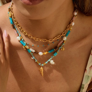 Détail d'un collier à plusieurs rangs en acier inoxydable avec pierres, perles et coquillage