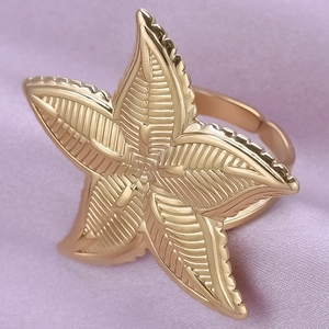 Macro detail of golden starfish ring featuring intricate texture on soft purple fabric