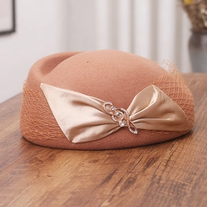 Detail of camel wool beret featuring champagne satin bow, diamond notes, and fine mesh veil