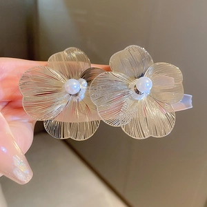 Detailed macro view of metal flower earrings with white faux pearl centers and wire petals