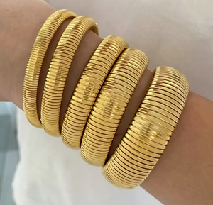 Detailed view of 5-piece gold tubogas stretch bracelets worn on wrist for style