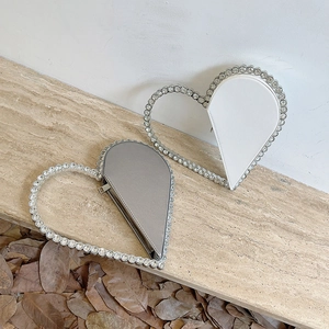 Elegant heart-shaped evening clutch bags with crystal frame on stone surface