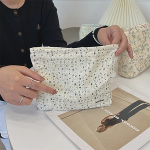 Detailed close-up of floral canvas cosmetic bag featuring delicate white lace trim