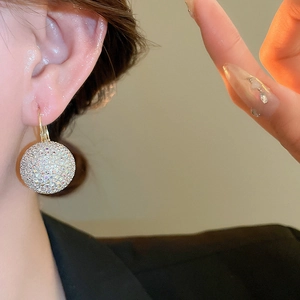 Close-up of a sparkling pavé diamond ball earring worn on a model for a luxury look