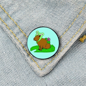 Macro detail of a cute capybara in frog hat badge pinned on blue denim fabric