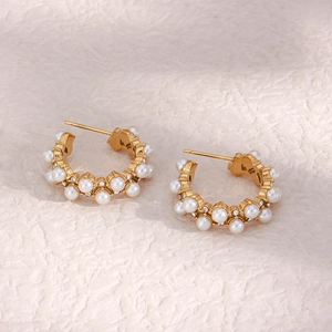 Detail of vintage C-shaped earrings with white pearls and small zircons on gold metal