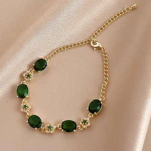 Bracelet fleuri élégant plaqué or avec pierres vertes sur fond en soie de couleur champagne