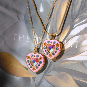 Detail of gold heart locket necklace with colorful crystals on a botanical book background