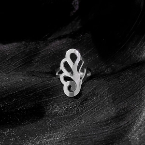 Macro shot of silver cutout floral pattern ring on a black textured background