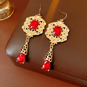 Macro shot of vintage gold earrings with deep red gemstones and small white diamonds