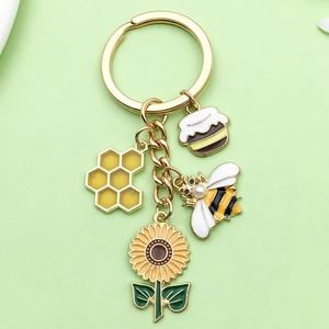 Enamel bee keychain with honeycomb, honey jar, and sunflower charms on a gold ring