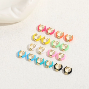 Macro detail of multi-colored enamel huggie earrings set with polished gold finish