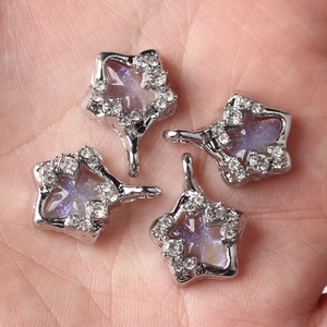 Star-shaped alloy pendants with purple resin inlay and sparkling crystals held in palm