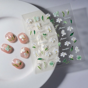 3D relief nail stickers featuring white floral patterns and green leaves on nails