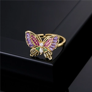 Golden butterfly ring with colorful cubic zirconia crystals on a black reflective base