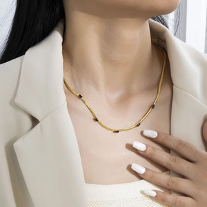 Close-up of gold snake chain necklace featuring five black rectangular zircon stones