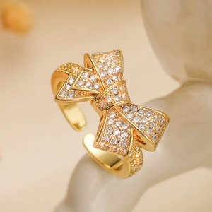 Luxurious 18K gold plated bow ring with zircon stones on a beige textured stand