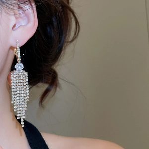 Close-up of elegant tassel earrings with silver zirconia chains on a model's ear