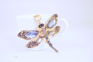 Macro shot of dragonfly keychain with purple rhinestones on a white teacup rim