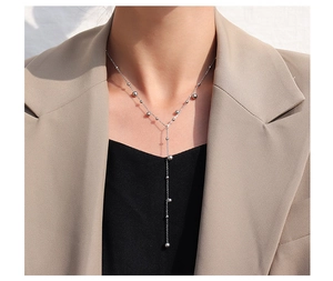 Silver bead fringe necklace displayed on a model wearing a beige blazer and black top
