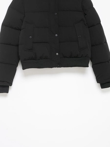 Détail de veste d'hiver noire avec boutons-pression en métal et ourlet côtelé