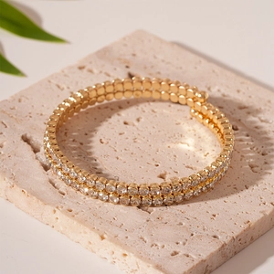 Close-up of double-row paved crystal open bangle with golden finish on stone background