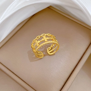Détail de la bague trèfle dorée avec design ajouré triple couche dans un écrin