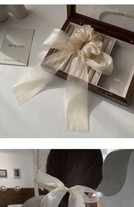 Close-up of a large cream organza bow hair clip displayed in a wooden jewelry box