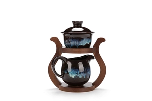 Detail of dark ceramic tea set with blue drip glaze on a custom bamboo stand