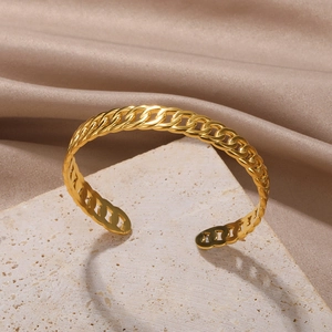 Detailed macro of golden flat curb link open cuff bracelet on elegant stone surface