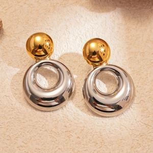 Vue détaillée des boucles d'oreilles créoles bicolores sur une surface en pierre texturée