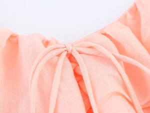 Detail of pink chiffon dress neckline with delicate tie-knot bow and soft fabric texture