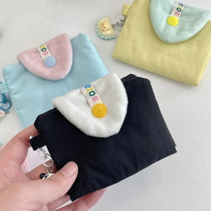 Détail rapproché de mini porte-cartes colorés avec rabats en peluche et pendentifs