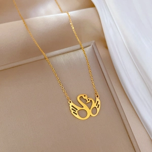 Detail of gold kissing swan pendant on a silk background in a beige jewelry gift box